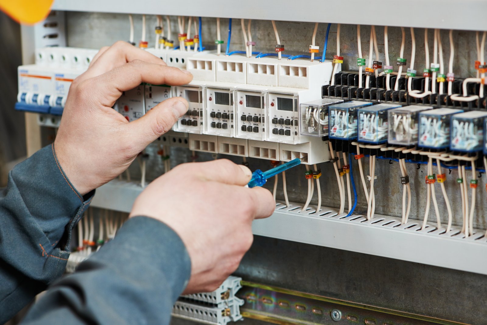 Technician working on an electrical panel with control devices