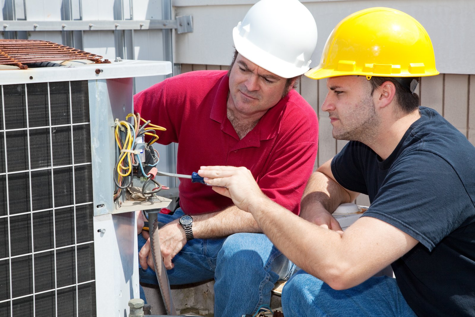 Two technicians inspecting an outdoor HVAC unit
