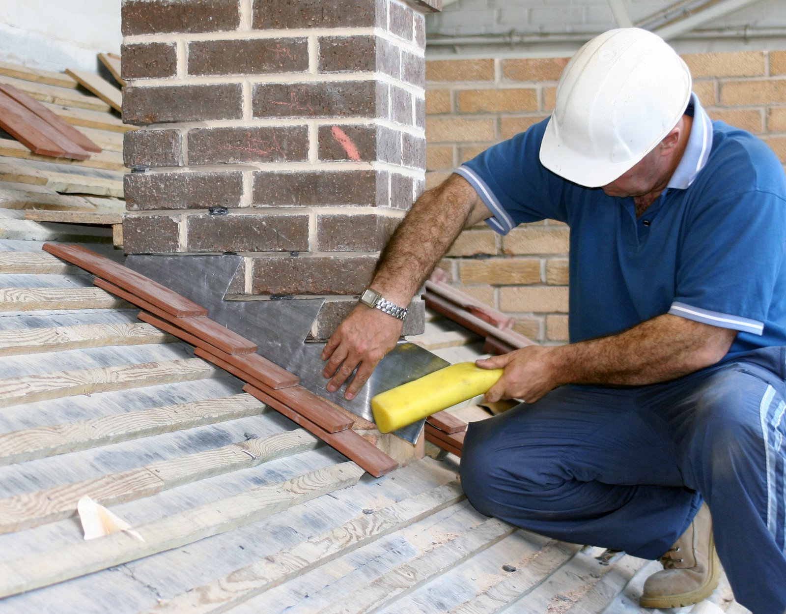 Worker fitting weatherproof flashing around a roof chimney